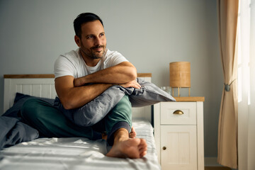 Wall Mural - Pensive man day dreaming while relaxing in bedroom.