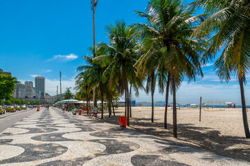 Wall Mural - Copacabana beach with palms and mosaic of sidewalk in Rio de Janeiro, Brazil. Copacabana beach is the most famous beach in Rio de Janeiro. Sunny cityscape of Rio de Janeiro