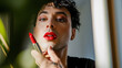 © Julija - man transgender applying lips with red lipstick , making makeup.
