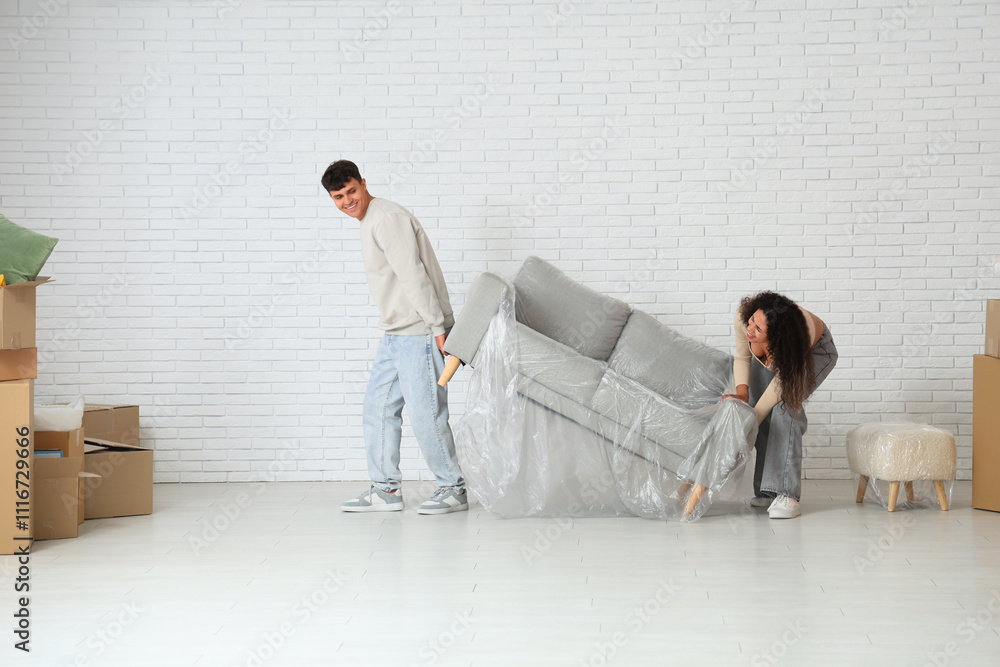 Young couple placing packed sofa in their new flat