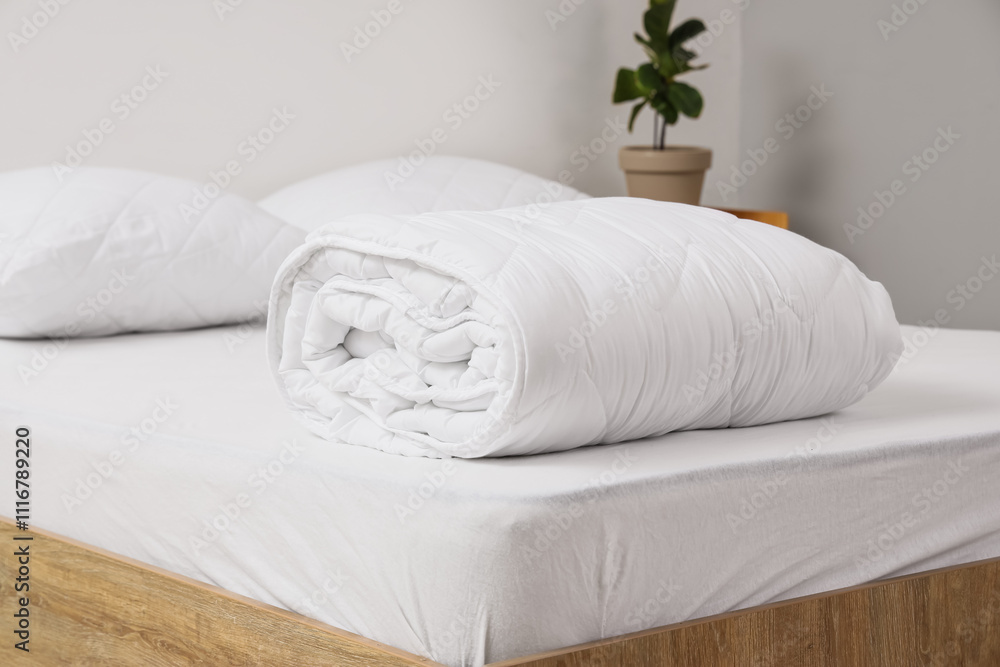 Folded blanket on bed in light room, closeup