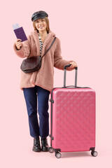 Wall Mural - Female tourist with passport and suitcase on pink background