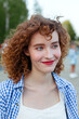 © Viktor Solomin/Stocksy - A young woman with curly hair smiles warmly closeup portrait