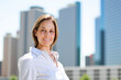 © Minerva Studio - Businesswoman smiling with city skyline in background
