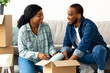 © Prostock-studio - Moving To New House. Happy African American Spouses Packing Belongings Into Cardboard Boxes At Home, Cheerful Black Couple Smiling To Each Other, Ready For Relocation To Their Own Apartment, Closeup