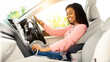 © Prostock-studio - Riding In The City. Profile side view of happy black woman sitting in modern vehicle, driving her new auto, holding steering wheel and gear shift. Experienced female driver enjoying trip and travel