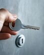 © Frame - A hand inserting a key into a lock on a textured wall.
