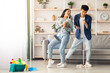 © Prostock-studio - Funny asian loving couple singing songs while cleaning apartment, using broom and mop as microphones, cheerful beautiful young man and woman imitating rock stars while house-keeping, copy space