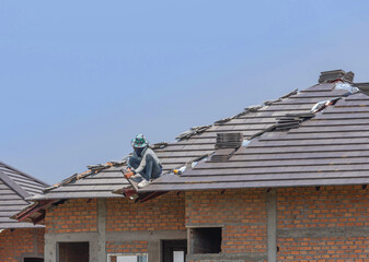 Wall Mural - Roofer installing concrete tiles on the roof house in residential construction site