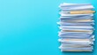 © Cerita - High stack of papers and a pen on a vibrant blue background.