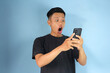 © Lailar Studio - Young Asian man looking his mobile phone with shocked expression