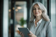 © PixelPulse Creative - Smiling mature professional business woman, executive or lady entrepreneur holding digital tablet