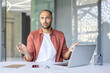 © Liubomir - Portrait of upset and disappointed businessman, man looking displeasedly at camera while sitting inside office with laptop at workplace.