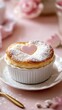 © Alex - Delicate souffl? topped with a pink heart, dusted with powdered sugar, set in an elegant white ramekin on a pink backdrop.