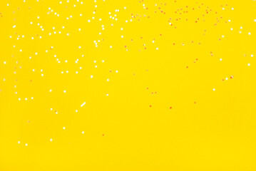 Wall Mural - Tiny pearl stars on yellow background. Flat lay, top view.