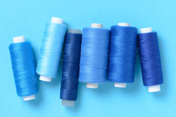 Wall Mural - Blue thread spools background with copy space for text close-up flat lay top view