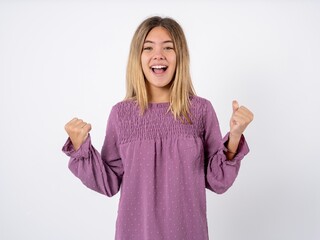 Wall Mural - Beautiful teenager girl wearing purple T-shirt  celebrating surprised and amazed for success with arms raised and open eyes. Winner concept.