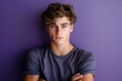 © Alla - A young man stands with his arms crossed against a purple wall, looking confident and relaxed