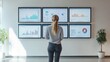 © Bambalino Studio - A woman stands in front of a wall of monitors displaying graphs and charts. She is focused on the data displayed on the screens. The room has a modern and professional atmosphere