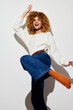 © SHOTPRIME STUDIO - Happy woman dancing in casual outfit, beige sweater, blue jeans, joyful expression, white background, capturing carefree spirit and energy, perfect for lifestyle concepts