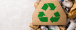 © PBMasterDesign - Recycling symbol on cardboard among various types of waste for sustainable practices.