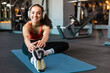 © Home-stock - Happy European sporty woman warming up before training, wearing headphones listening to music and stretching, smiling at camera