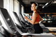 © Home-stock - Beautiful happy fit woman running on treadmill and enjoying music wearing headphone during sports training in modern gym