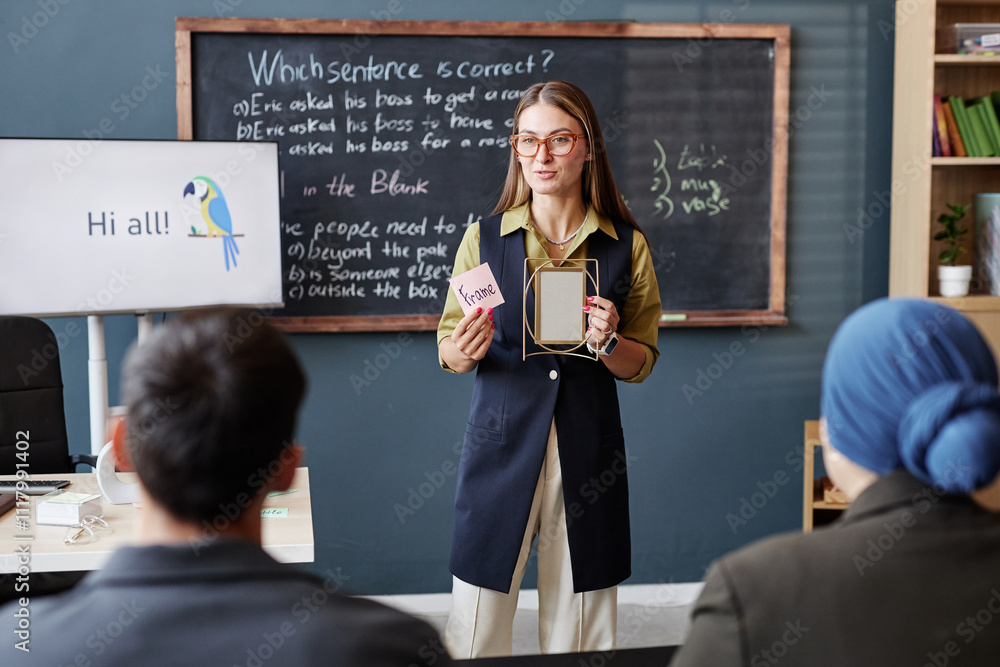 Medium full shot of young female English language instructor talking to ...