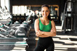 © Home-stock - Portrait of European fit woman wearing sportwear bra and pants posing with folded arms in fitness gym interior. Sports and healthcare concept
