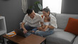 © Krakenimages.com - Couple sitting with baby in living room using laptop, showing love and family bonding indoors with chinese parents and toddler together on a comfortable sofa.