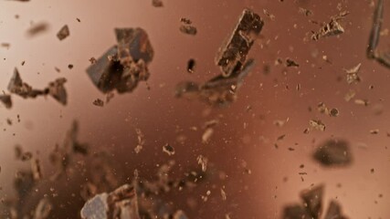 Poster - Super Slow Motion of Flying Chocolate Chunks in the Air. Isolated on Brown Background. Filmed on High Speed Cinema Camera, 1000 fps.