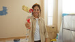© Krakenimages.com - Woman painting with roller in new apartment, smiling in renovated living space.