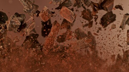 Poster - Super Slow Motion of Flying Chocolate Chunks up in the Air. Isolated on Brown Background. Camera Moving Around. Filmed on High Speed Cinema Camera, 1000 fps.