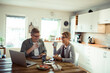 © Davor - Happy senior couple eating breakfast with laptop on desk