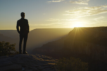 Wall Mural - Man gazes at sunset over Grand Canyon during golden hour