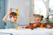 © Arianne - Two brothers eating spaghetti with tomato sauce at home
