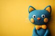 © Michael - Cute blue felt cat toy with orange nose and yellow bow tie on a vibrant yellow background, perfect for children's projects or pet-related designs