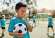 © Running opossum - Child soccer player holding a ball and covering his nose on a field during a sunny day