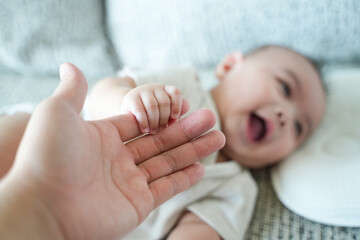 close up of the baby holds the mother's finger.