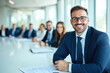 © Tondone - Smiling businesspeople sitting at the table in a conference room, working together on a project with a whiteboard and papers