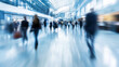 © Alexander - Busy airport with people walking around and carrying luggage. The image is blurry, giving it a sense of motion and activity