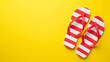© fotoluigi868 - A vibrant yellow backdrop features a pair of red striped flip flops in a flat lay design ideal for summer advertisements and promotions._00001_