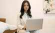 © RooftopStudioBangkok - business woman in white suit working on laptop in modern setting, exuding professionalism and focus. clean background enhances her presence