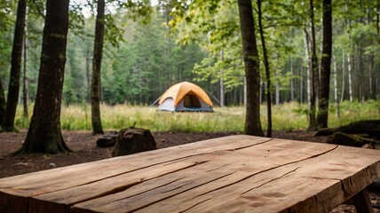 a empty wooden table in the foreground with a tent and trees in the blurred background, suggesting a