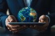 © amirfaoezan - Businessman holds a holographic Earth globe on a tablet, symbolizing global connectivity.