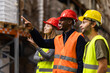 © Nikola Spasenoski - Diverse warehouse workers in safety gear discussing logistics and storage