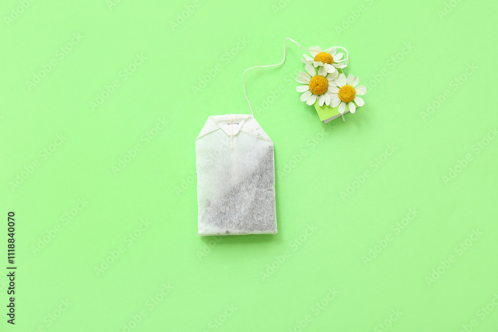 Tea bag with chamomile flowers on green background. Top view