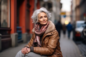 Wall Mural - Mature woman sitting on a bench in the city street. Portrait of an elderly woman.