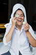 © Marcos - Latin adult woman applying facial mask on face with cucumber slices for exfoliation at home in Mexico Latin America, hispanic people