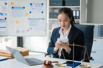 Wall Mural - A young Asian woman in a suit works at her desk, reviewing legal documents. lawyer advice on contracts, finance, agreements, demonstrating professionalism and authority in business setting.